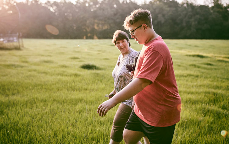 Boy Walking in Field With Mom