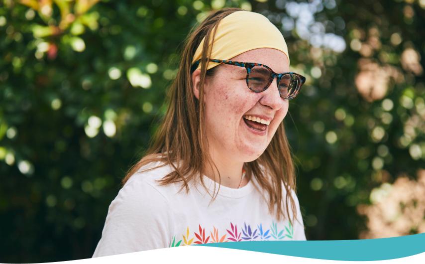 Kelley, living with TSC, smiling with trees in the background